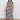A person poses confidently in Sanctuary Clothing's contrast trim maxi dress in black macrame stripe, extended sizing, featuring side slits and paired with black sandals against a plain light-colored wall and floor.
