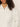A person with curly dark hair models the Sanctuary Clothing cropped paper boy jacket in bleached white, featuring a collar and chest pocket. The image is cropped at the mouth, omitting the full face and lower part of the jacket.