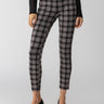 A person is wearing Sanctuary Clothing's Runway Legging Almond Plaid paired with a black long-sleeve top. The outfit is completed with black pointed-toe kitten heels. The background is plain and neutral, emphasizing the clothing and footwear.