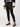 A person is wearing the Runway Legging Faux Suede Black by Sanctuary Clothing, paired with black flat shoes. The person is also wearing a long-sleeved, black and white color-blocked sweater. The image focuses on the lower half of the body against a plain background.