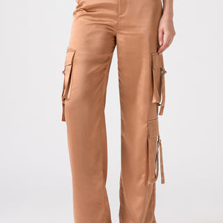 A person wearing the Y2K Strappy Cargo Mocha Mousse pants from Sanctuary Clothing, featuring a high-waisted, wide-leg design in tan with multiple pockets and side buckles, paired with open-toe block-heeled sandals. The background is plain white.