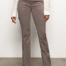 A person is wearing the Sculpted Hayden Bootcut Cocoa pants from Sanctuary Clothing, featuring a high-waisted fit with a front button and pockets. Pairing these stylish brown cargo pants with a white knit sweater and black ankle boots creates an elegant look in a neutral indoor setting.