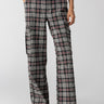 A person is wearing the Gwen Cargo Garnet Plaid trousers from Sanctuary Clothing, which feature a high-waisted, wide-leg design with a black, white, and red checkered pattern. The pants have side cargo pockets. The wearer is also dressed in a long-sleeve red top and black pointed-toe shoes.