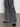 A person wearing the speed denim cargo odyssey pants from Sanctuary Clothing, featuring wide-leg gray denim and multiple pockets, pairs them with black pointed-toe shoes while standing on a gray floor against a white wall.