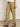 A person in Sanctuary Clothing's "take over linen jogger standard rise pant" in bamboo is wearing brown sandals. The pants feature large side pockets and elastic cuffs. They're standing on a beige floor with a white wall background.