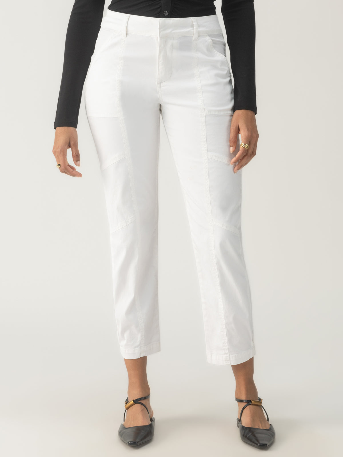 A person is wearing a black long-sleeve top paired with the Sahara Tapered Pant Chalk from Sanctuary Clothing. The close-up view captures the outfit from waist to feet against a neutral background, complemented by black pointed shoes.