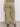 Someone is wearing the Sanctuary Clothing area standard rise pant bamboo extended sizing in olive green, with large back and side pockets, paired with black sandals and a striped top, standing against a plain light background.