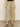 A person wears Sanctuary Clothing's area standard rise pant bamboo in light olive green with a drawstring waist and wide legs, paired with black heeled sandals, standing on a beige floor against a plain light wall.