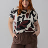 A person with long red hair is wearing The Perfect Tee Light Mineral Inclusive Collection from Sanctuary Clothing, paired with brown cargo pants. They have their hands in their pockets and are standing against a plain gray background.