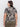 A person with long, dark hair is facing away, wearing Sanctuary Clothing's "the perfect tee mirage" with beige and black patterns, along with olive green pants. They have gold hoop earrings against a plain gray background.