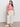A person in Sanctuary Clothing's the perfect tee sunny riviera extended sizing, featuring a red and white pattern, paired with light beige wide-leg pants. They wear white sneakers and have long dark hair, standing against a plain background.