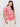 A woman models the Sanctuary Clothing "perfect tee sunny riviera extended sizing," featuring a bold red sun and wave pattern, paired with cream pants against a plain white backdrop. She has long, dark hair.