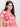 A person with long dark hair dons Sanctuary Clothing's "the perfect tee sunny riviera extended sizing," featuring a cream background with red abstract sun designs. Complementing gold hoop earrings, they gaze sideways against a plain backdrop.
