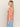 A person with long, straight hair is shown in profile, wearing the Sanctuary Clothing "The Perfect Tee Sunny Riviera" featuring a cream and red abstract pattern, paired with light blue jeans against a plain off-white background.