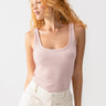  A person with long, curly, red hair is wearing the My Kind Of Tank Smokey Rose from Sanctuary Clothing and cream-colored pants. They are looking to one side with a calm expression against a plain white background.