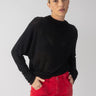 A person with light hair is wearing a black Sheer Stripe Funnel Neck Top by Sanctuary Clothing and red pants. They stand against a plain background, looking at the camera with a neutral expression.