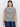 A person with long dark hair wears the perfect textured tee macrame black stripe from Sanctuary Clothing, paired with blue jeans. They're standing against a plain white background, sporting hoop earrings and a neutral expression.