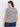 A person with long dark hair faces away, donning Sanctuary Clothing's perfect textured tee in macrame black stripe. They pair it with dark jeans and gold hoop earrings against a plain white background.