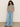 Person wearing Sanctuary Clothing's perfect textured tee in macrame black stripe and wide-leg blue jeans, standing with hands in pockets. They have long, curly hair and are smiling against a plain, light-colored background.