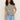 A person with long curly hair, wearing Sanctuary Clothing's "perfect textured tee macrame black stripe" and light blue jeans, stands against a plain background with a relaxed posture and one hand on their hip.