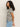 A person with curly hair is wearing Sanctuary Clothing's perfect textured tee macrame black stripe and light blue jeans. They are standing sideways against a plain background, looking to the left.