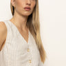 A person with long, straight blonde hair wears Sanctuary Clothing's relaxed modern vest in natural metallic stripe. They stand against a plain background, looking slightly to the left.