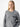 A person with long blonde hair is wearing the Uptown Girl Sweater Heather Ash from Sanctuary Clothing, featuring a black-trimmed front pocket. They are standing against a plain white background and gazing directly at the camera with a neutral expression.