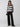 A person with long hair is wearing the Sanctuary Clothing Picture This Stripe Sweater in Ash Multi Stripe and black wide-leg pants. They have one hand in their pocket and are looking slightly to the side against a plain gray background.