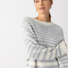 A person wearing the Sanctuary Clothing Fuzzy Tunic Sweater in Pearl Blue Chalk Stripe looks to the side against a plain white background. They have long hair pulled back and are adorned with small hoop earrings.