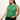 A woman in a Sanctuary Clothing open stitch shell sweater palm inclusive collection, paired with black pants, poses against a plain background. With long brown hair, she accessorizes with hoop earrings and layered necklaces, gazing downwards.