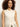 A woman with curly hair models the Sanctuary Clothing long openwork vest macrame, a sleeveless cream knit button-up worn over a white top, standing against a plain light background.