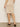 A person is seen from the back wearing the Sanctuary Clothing sequin pencil skirt in sandstone with open-toe heeled sandals, standing against a plain light-colored wall. Their back and legs are visible.
