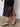 A person wearing the Sanctuary Clothing promenade halter dress in black stands on a smooth concrete floor, paired with black strappy flat sandals.
