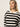 A woman with straight blonde hair models the Sanctuary Clothing open knit bomber jacket macrame black stripe, paired with gold hoop earrings, looking slightly upward against a plain light background.