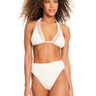 A woman with curly hair is wearing the Sea Crochet Triangle Halter Bikini Top in White Sand by Sanctuary Clothing and high-waisted textured bottoms. She is standing against a plain white background.